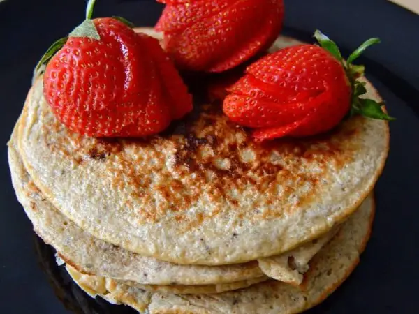 Deliciosas tortitas de avena y plátano, coronadas con fresas rojas y jugosas. Un desayuno perfecto.